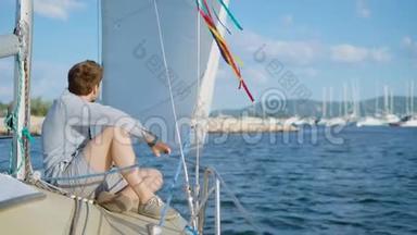 一个年轻人坐在一艘游艇的甲板上，这艘游艇已经离开码头，驶向海洋或大海